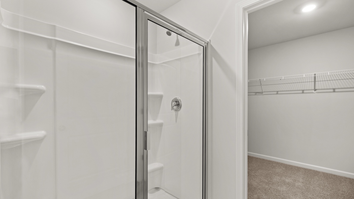 Interior primary bathroom with shower and walk-in closet