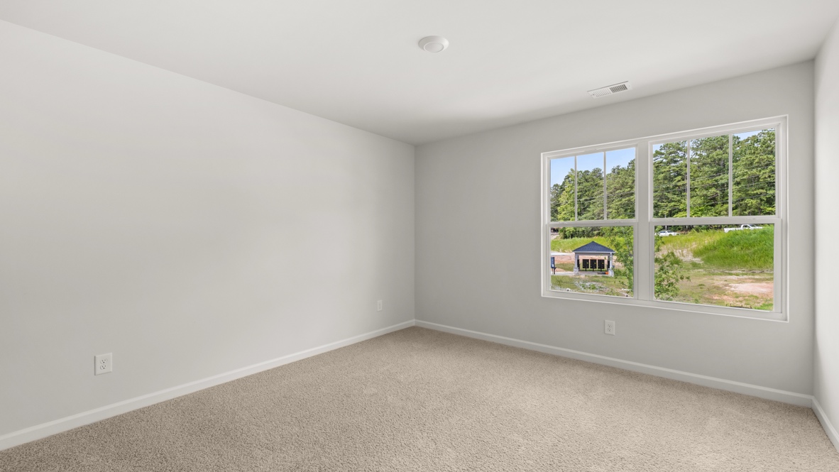 bedroom with beige carpet, grey walls and a window