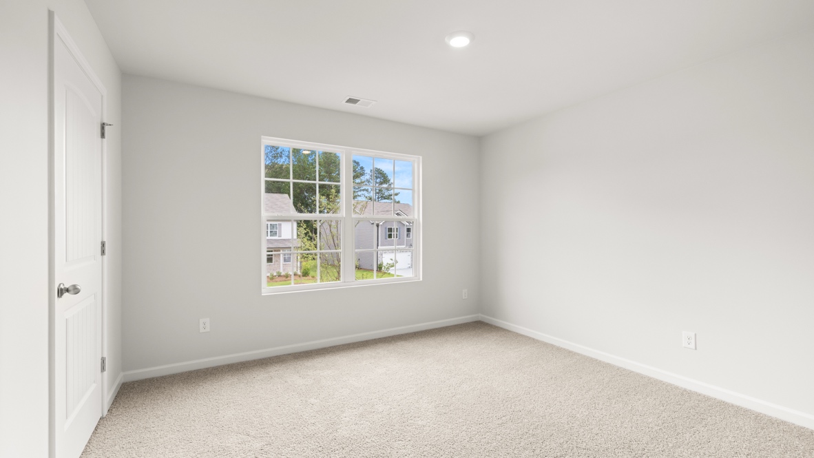 bedroom with beige carpet, grey walls and a window