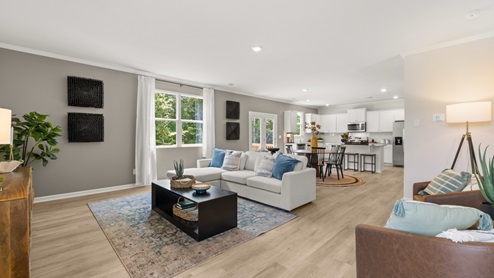 Spacious living room with brown flooring, white walls and windows