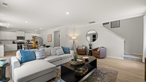 Spacious living room with brown flooring, white walls and windows