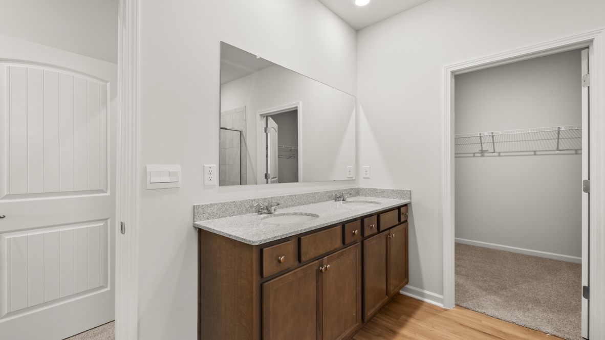 Interior primary bathroom with double sink and walk-in closet