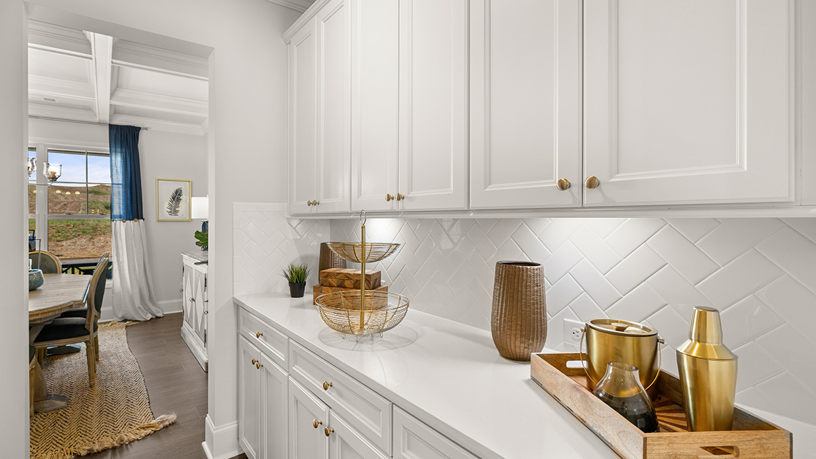 Bright white kitchen featuring sleek cabinets, a herringbone backsplash, and wood floors leading to glass doors, creating an open and modern feel.