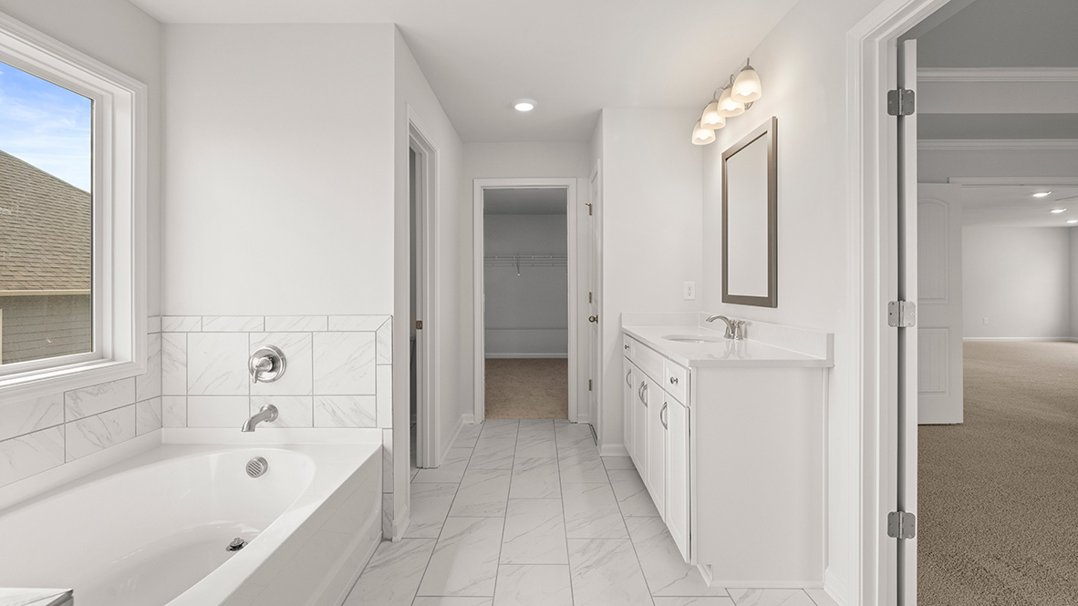 Interior primary bathroom with bath tub and sink