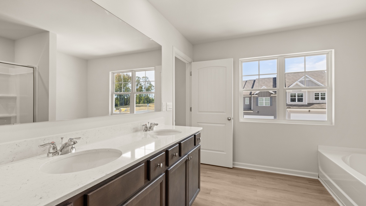 Interior primary bathroom with double sink, bath tub and shower