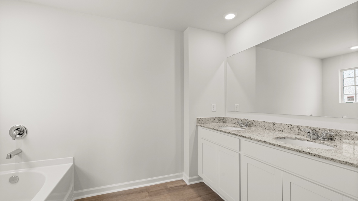 Interior primary bathroom with double sink and bath tub