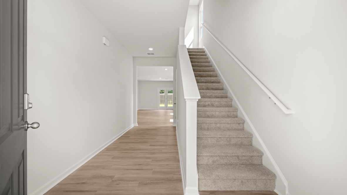 Interior entry-way open to staircase and leading to living area