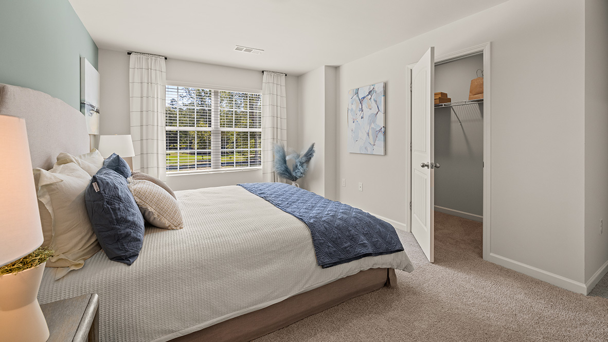 Interior primary bedroom with large window and closet
