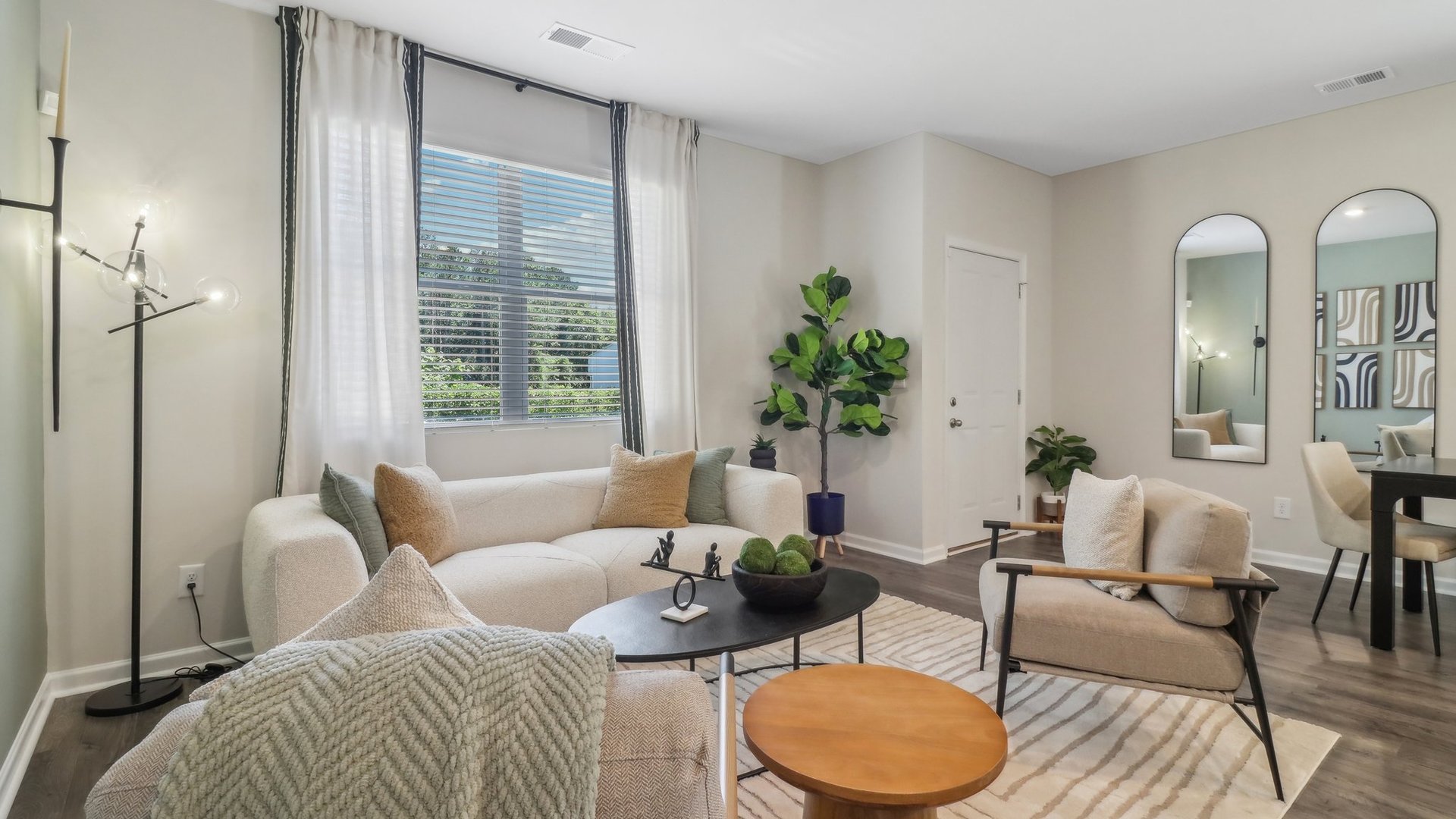 living room with light green accent wall, light grey couches, and a dining table seating 6