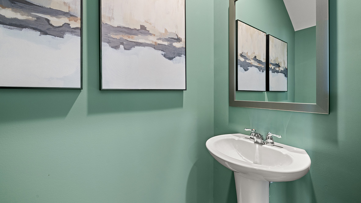 light green painted powder bathroom with a pedestal sink  and a mirror above