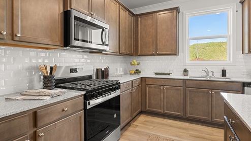 Large kitchen island with white countertops, white tile backsplash and brown shaker cabinets.