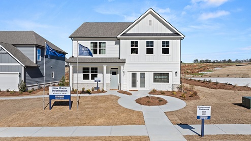 Exterior of Model home at Hamptons at Riverwood community. Two-story exterior home image with white siding, white trim and brick detail.