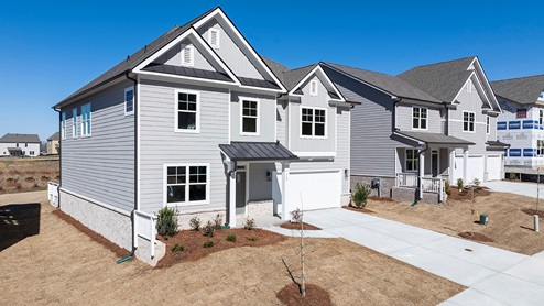 Two-story exterior home image with light gray siding, white trim, and two-car garages.