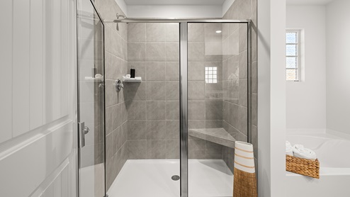 A full tile, standing shower with adjacent bathtub.