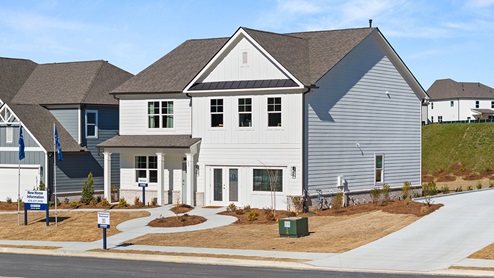 Exterior of Model home at Hamptons at Riverwood community. Two-story exterior home image with white siding, white trim and brick detail.