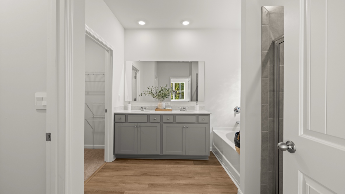 Interior primary bathroom with double sink next to shower and bathtub