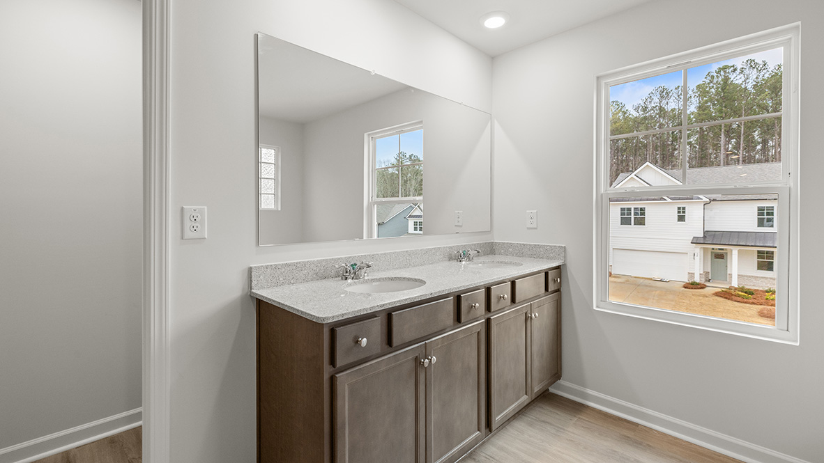 Interior primary bathroom with double sink and window