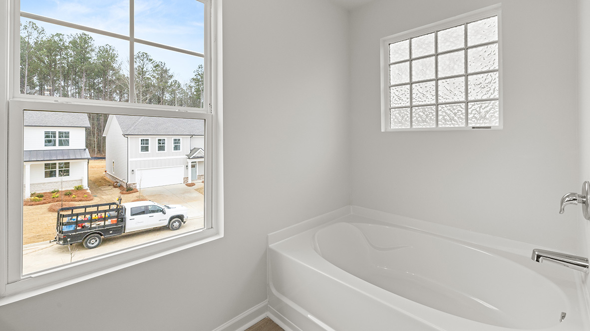 Interior primary bathroom with bath tub and window