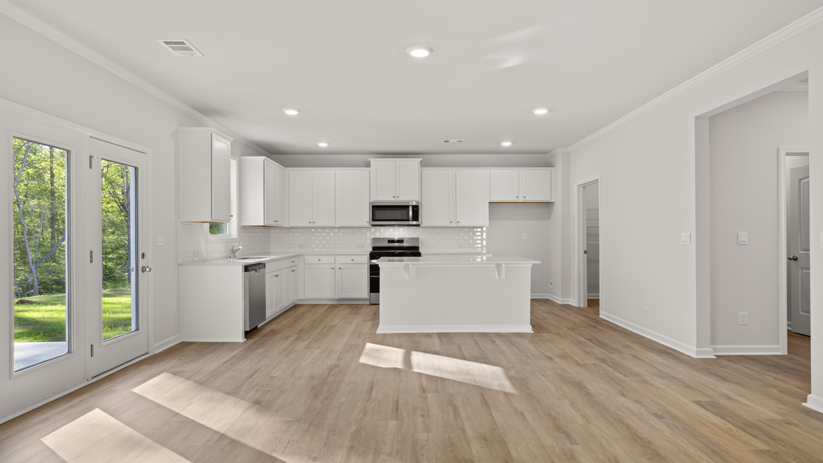 Interior living area open to kitchen with center island and white cabinets