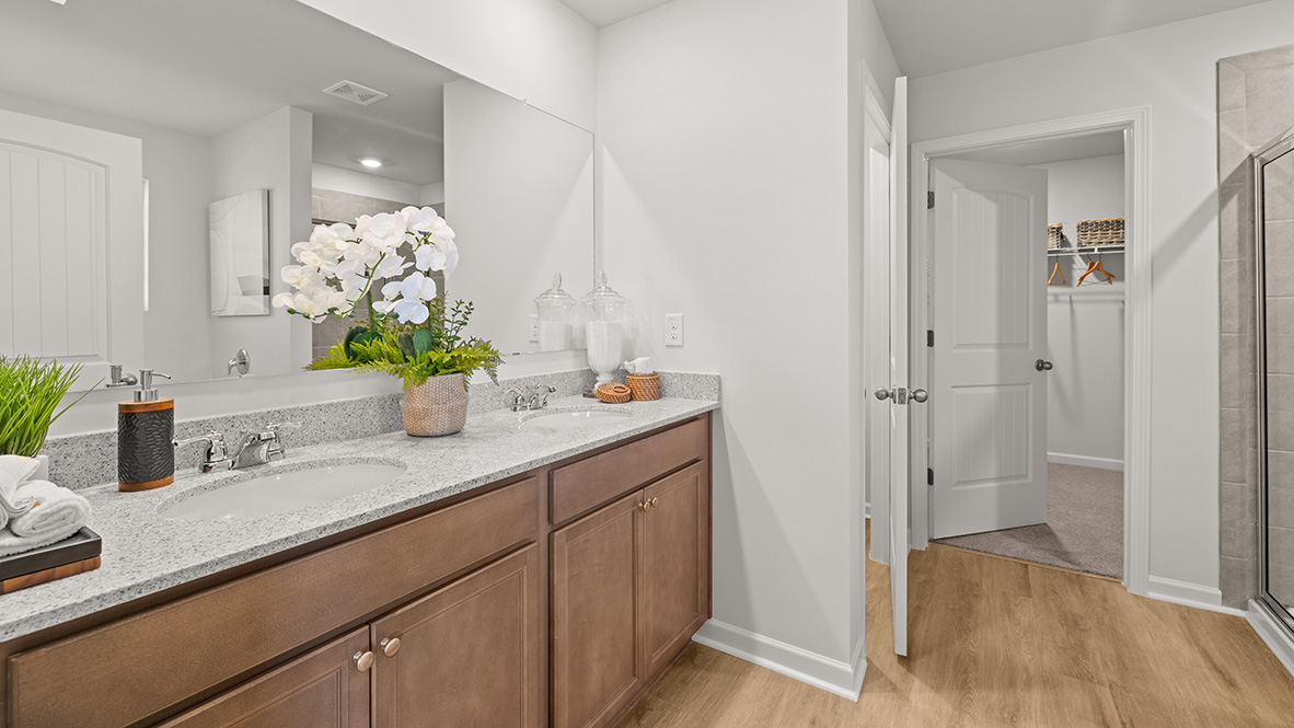 Interior primary bathroom with double sink next to bathtub and shower