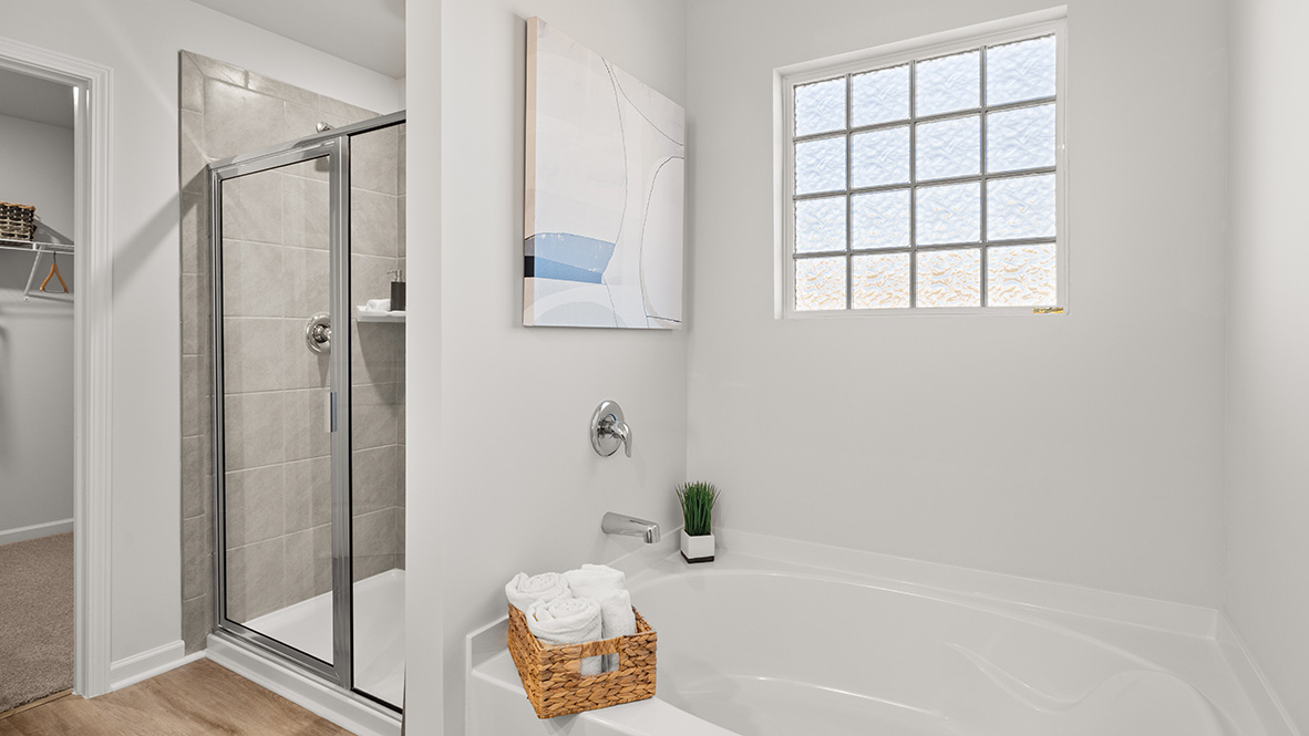 Interior primary bathroom with shower next to bathtub and window
