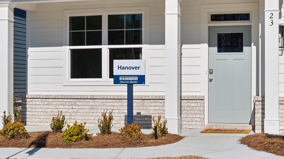 Exterior white two-story home with stone detailing and close-up of sign