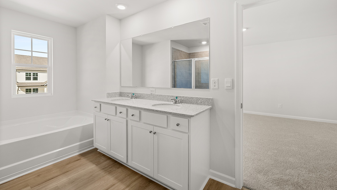 Interior primary bathroom with double sink and bath tub