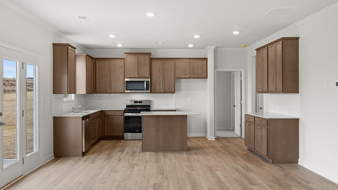 Interior kitchen with center island and wooden cabinets next to back door to patio