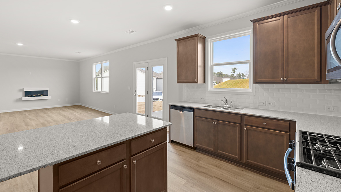 Interior kitchen with center island and wooden cabinets open to living area