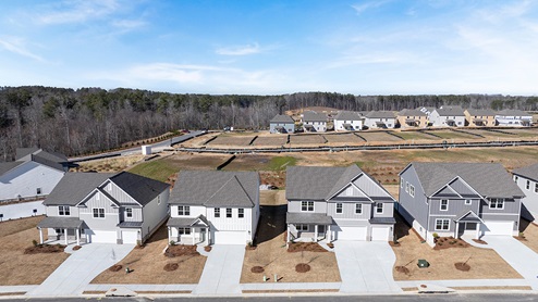 Drone image of multiple two-story elevations with white and gray siding, white trim and brick details.