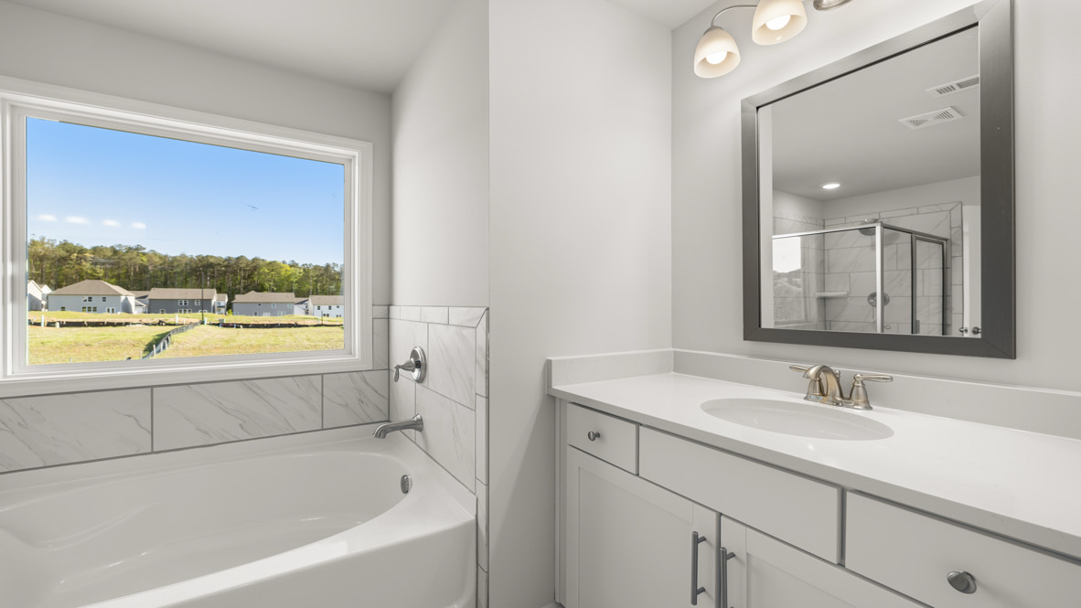 Interior primary bathroom with bath tub and sink