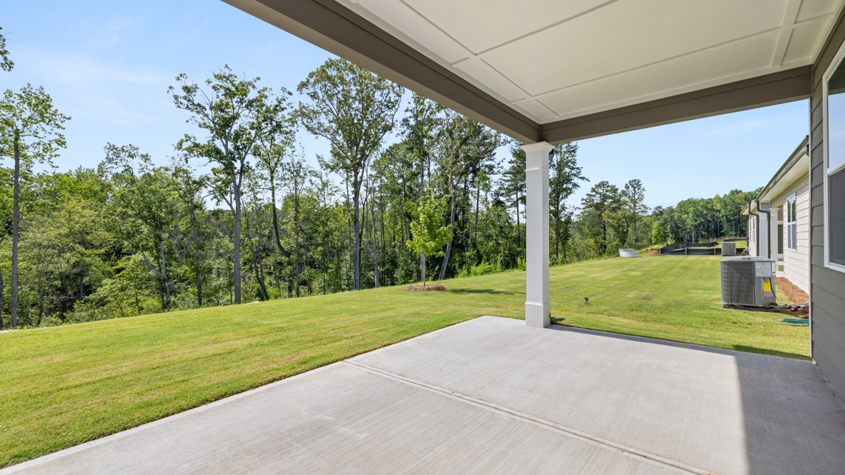 Covered patio with a concrete floor and a view of a large grassy backyard.