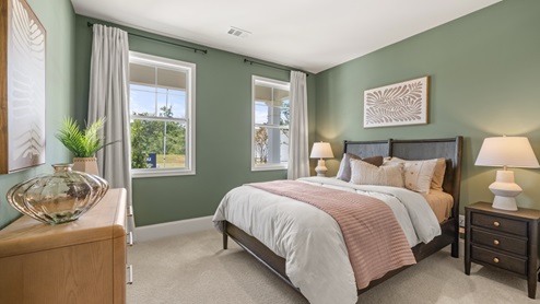 bedroom with green walls, a brown bed, and two windows