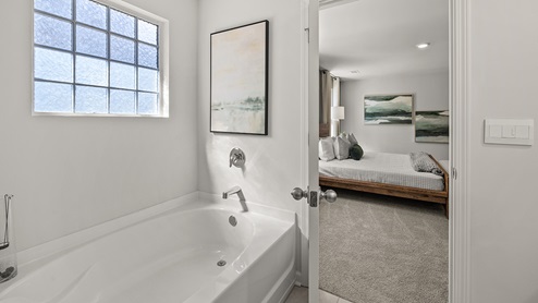 primary suite bathroom with a separate soaking tub