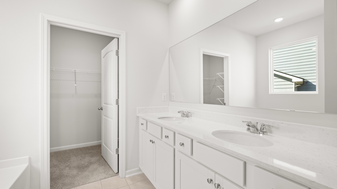 Interior primary bathroom with double sink and walk-in closet