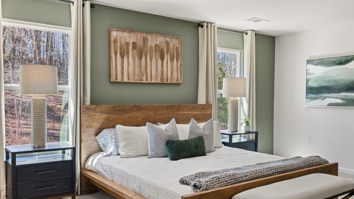 Interior primary bedroom with windows and accent wall