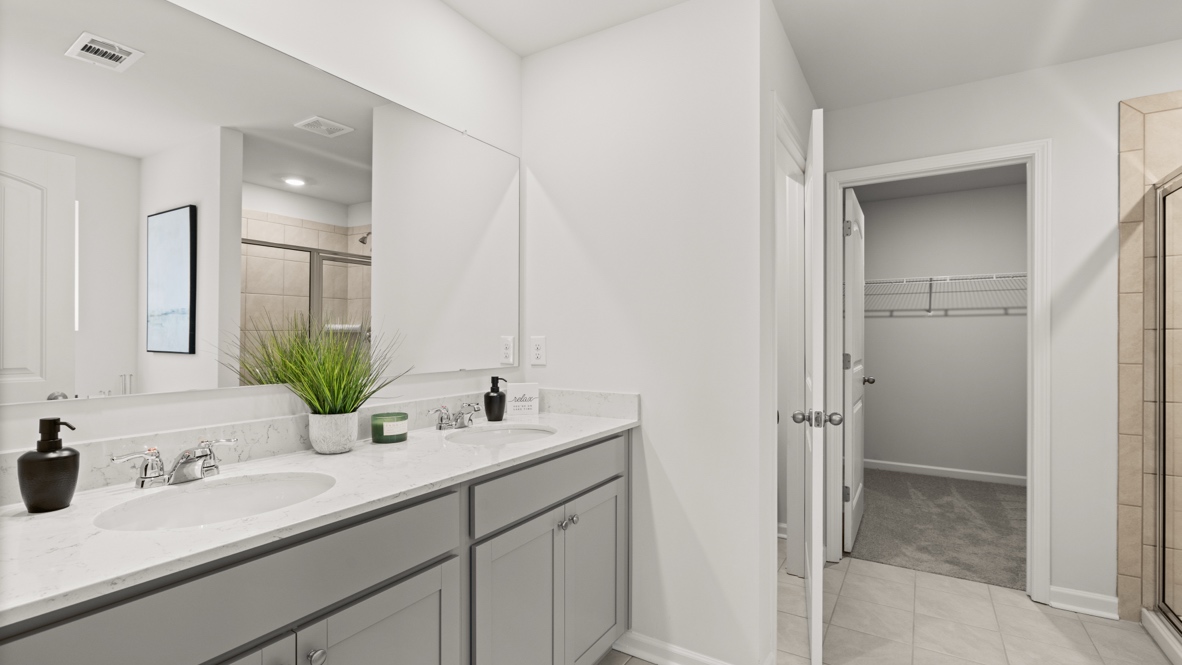 Interior primary bathroom with double sink and walk-in closet