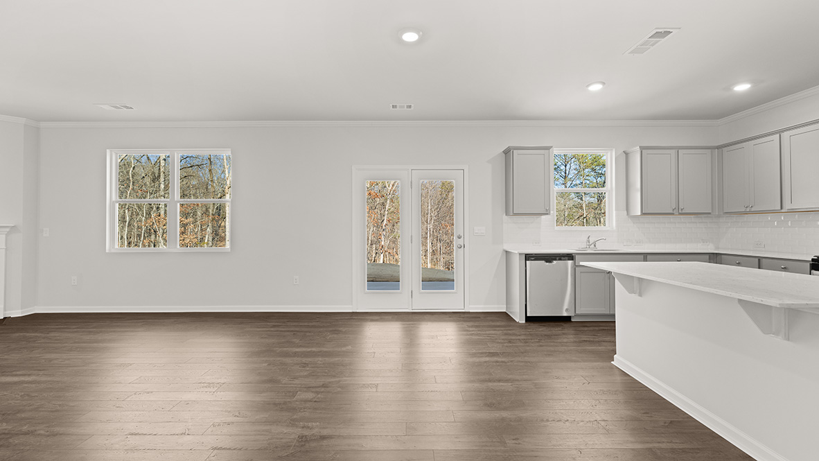 Spacious living room with brown flooring, white walls, a black fireplace and windows