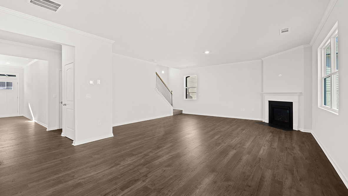 Spacious living room with brown flooring, white walls, a black fireplace and windows