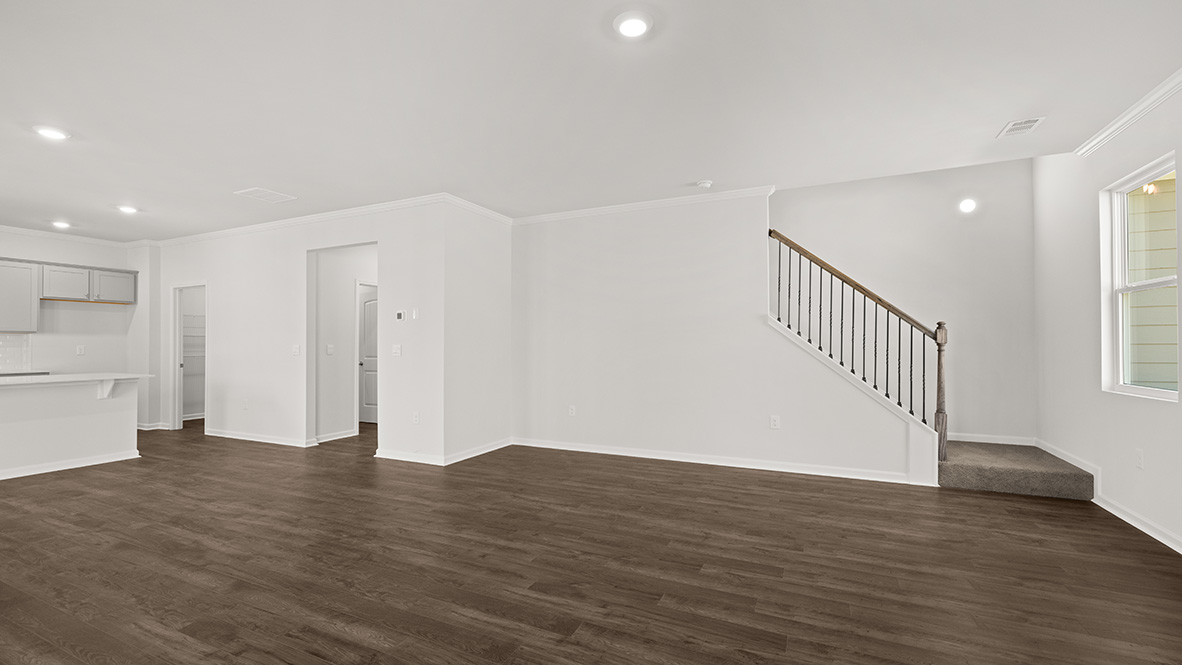 Spacious living room with brown flooring, white walls, a black fireplace and windows