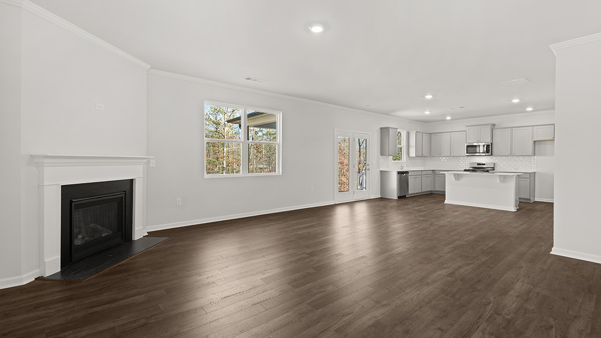 Spacious living room with brown flooring, white walls, a black fireplace and windows