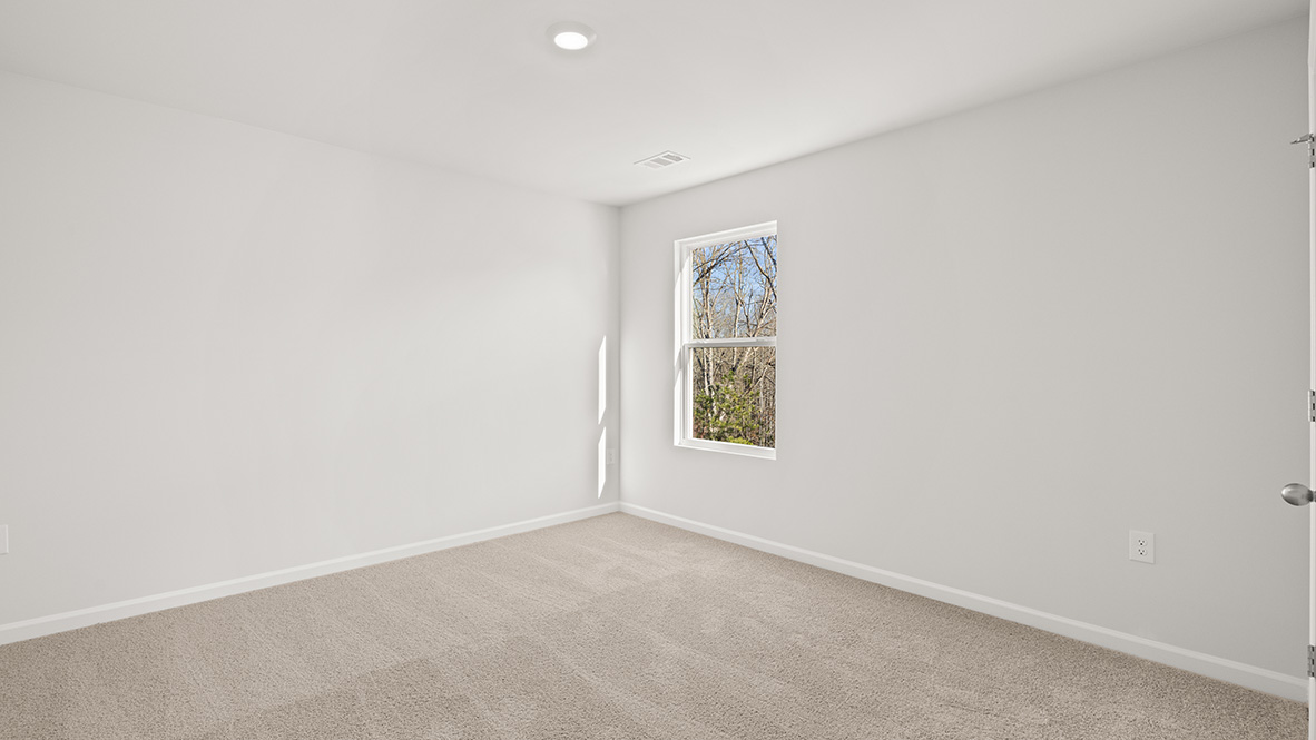 bedroom with beige carpet, white walls and a window