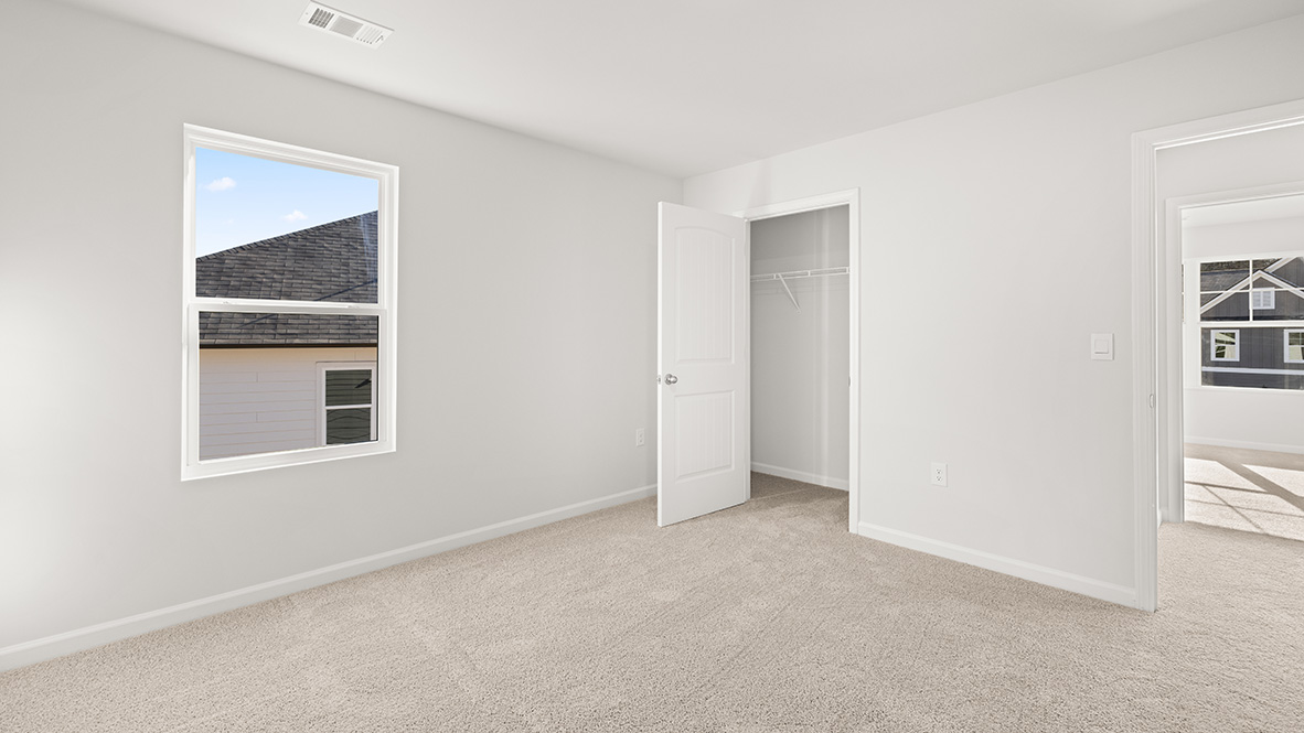 bedroom with beige carpet, white walls and a window