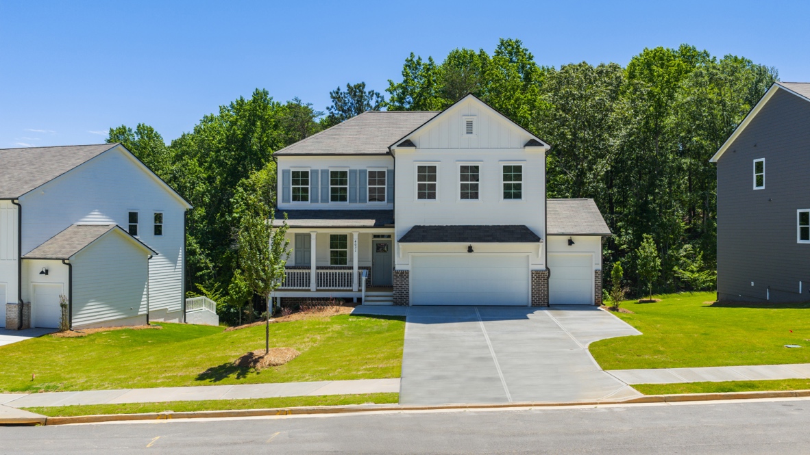 front exterior of two story home with white siding, a covered porch and a three car garage