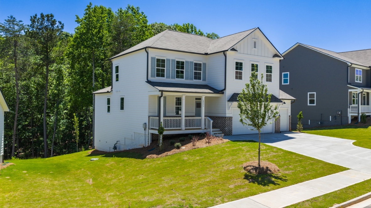front exterior of two story home with white siding, a covered porch and a three car garage