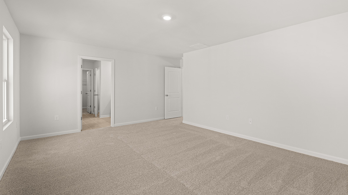 Bedroom 1 has a neutral carpet with a view of the ensuite bathroom and the entrance to the hallway.