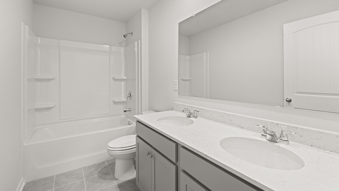 Full bathroom with a double vanity sink, white counter tops, grey shaker-style cabinets, a white shower with a tub.