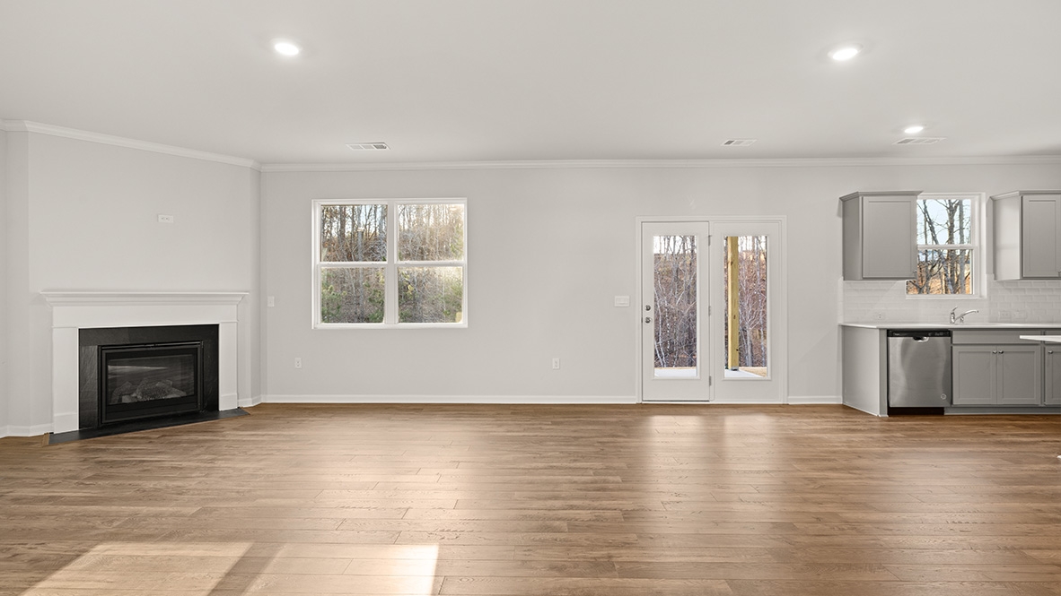 Spacious living room with brown flooring, white walls and windows