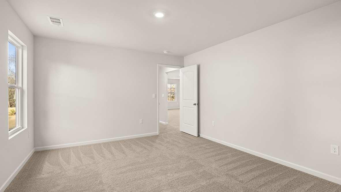 bedroom with beige carpet, white walls and a window