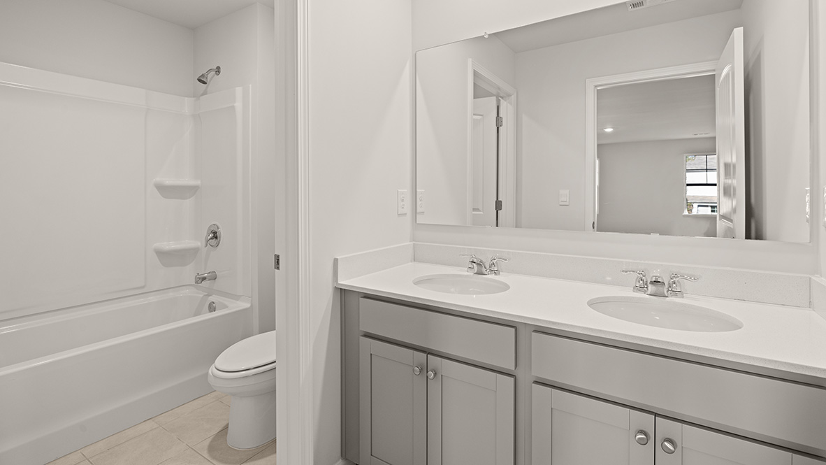 bathroom with dual vanity sinks, and a shower